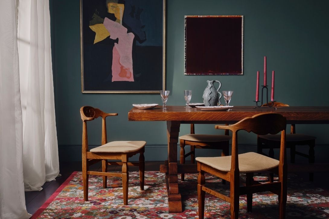 a dining table with chairs and a painting on the wall