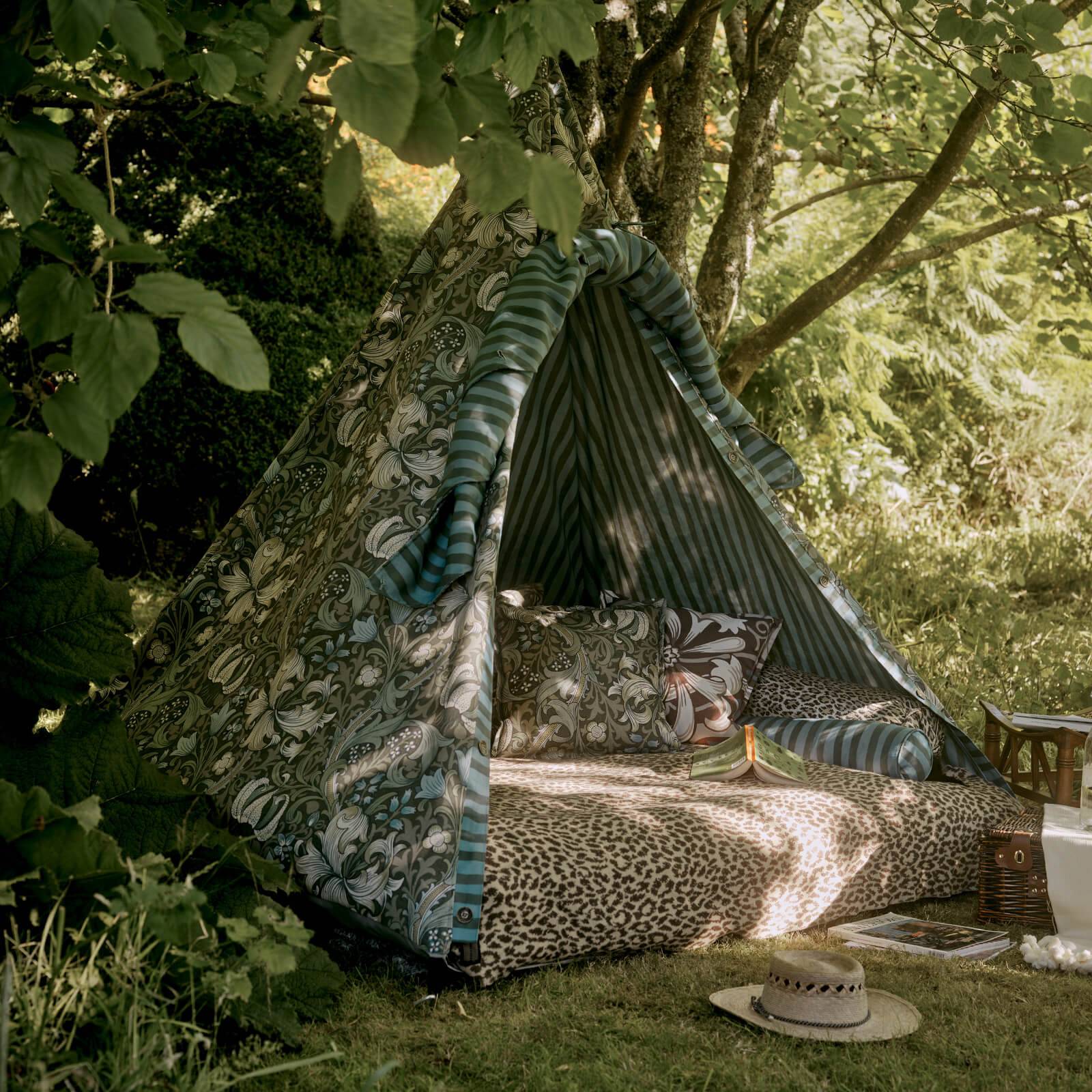 a tent with a blanket and a hat in the shade